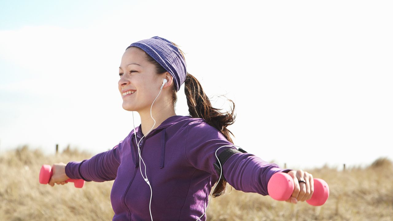 Woman completes a dumbbell workout outside 