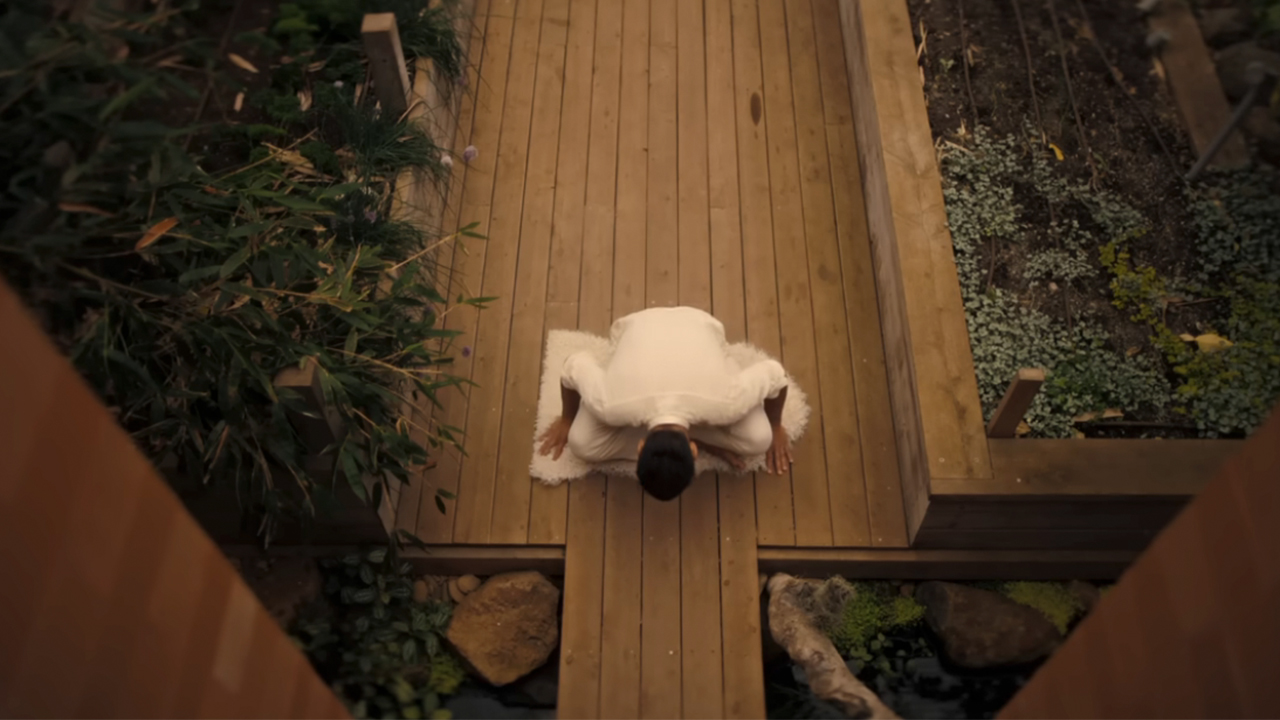 A person in all white doing yoga on a wood floor in Twisted Yoga