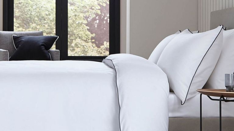 White bed linen with black piped edging on a bed in a modern bedroom