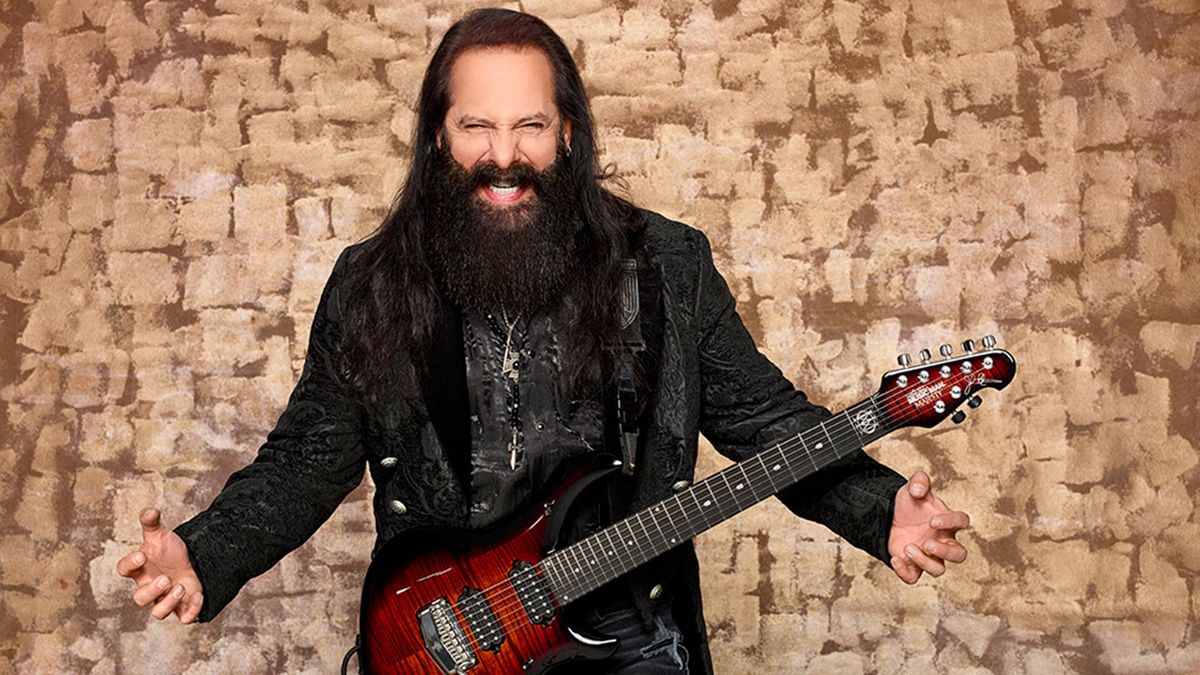 John Petrucci standing next to a wall with a guitar