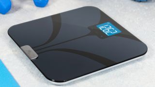 Weight Gurus Bluetooth Body Fat Smart Scale review: a shot of the scale next to some dumbbells