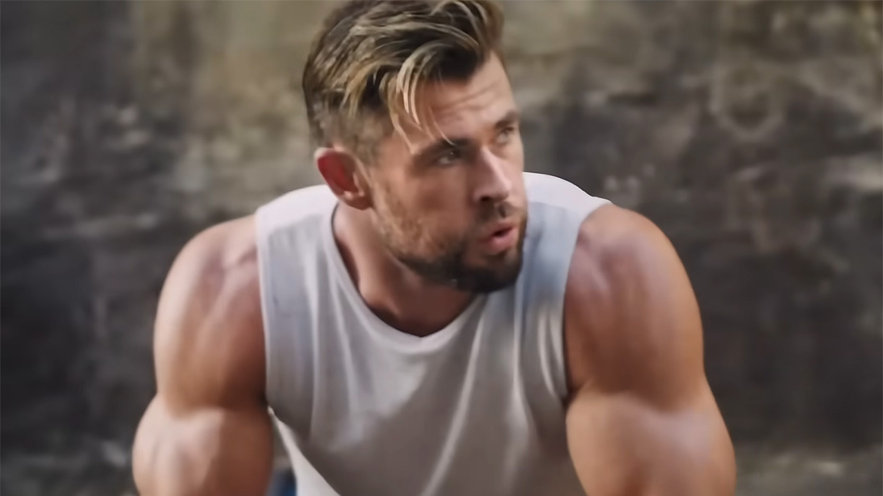 Chris Hemsworth looks to the right in a clip from a Centr ad. He's wearing a white tank and his arms are pumped up.