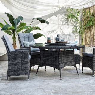 A rattan garden table and chair set on a paved patio