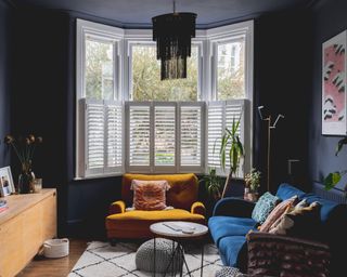 dark blue living room with bay window, sofa and yellow armchair