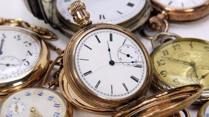 Antique pocket watches in a pile.