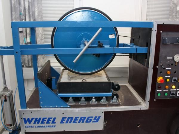 Tire friction is tested by controllably moving a small section of road material against a stationary wheel.