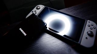 Nintendo Switch with Samsung S20 Ultra phone on dark background with bright circular light reflection