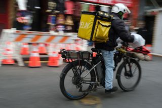 A delivery driver riding a converted e-bike containing two strapped on batteries