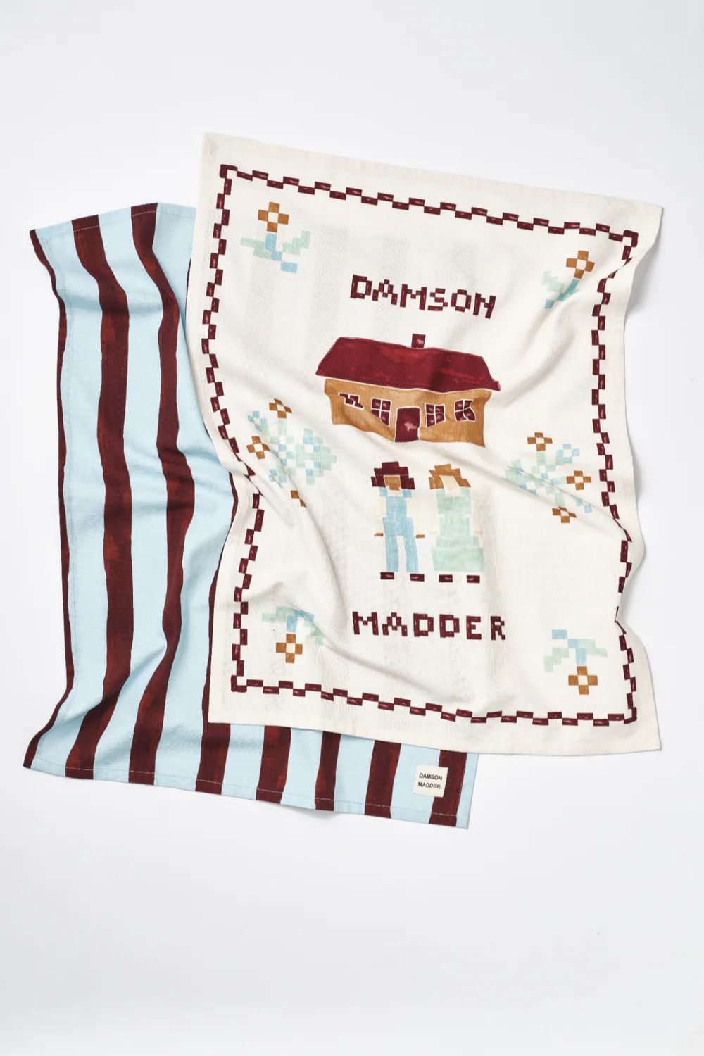 Tea towels with blue and burgundy stripe and Damson Madder patchwork logo illustration