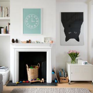 A white living room with a white fireplace and a storage basket filled with toys within it