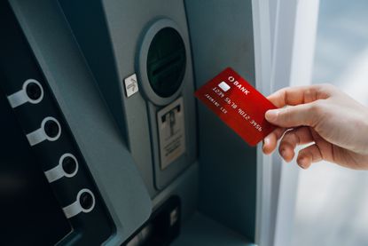 Person inserting bank card into ATM to access bank account services