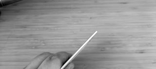 A silver Plaud Note voice recorder on a wooden desk