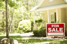 Home for sale with for sale sign in front yard.