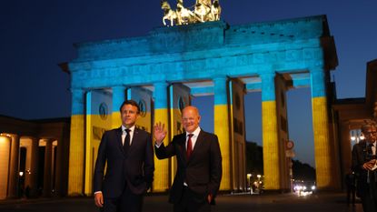 French President Emmanuel Macron and German Chancellor Olaf Scholz stand in front of the Brandenburg Gate