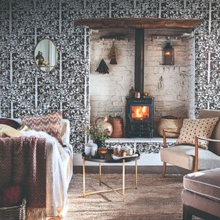 A rustic living room with a wall covered in a brown botanical wallpaper