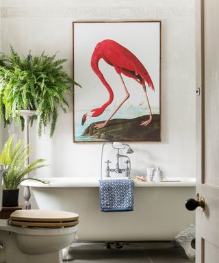 traditional bathroom with roll-top bath with flamingo wall art and fern plants