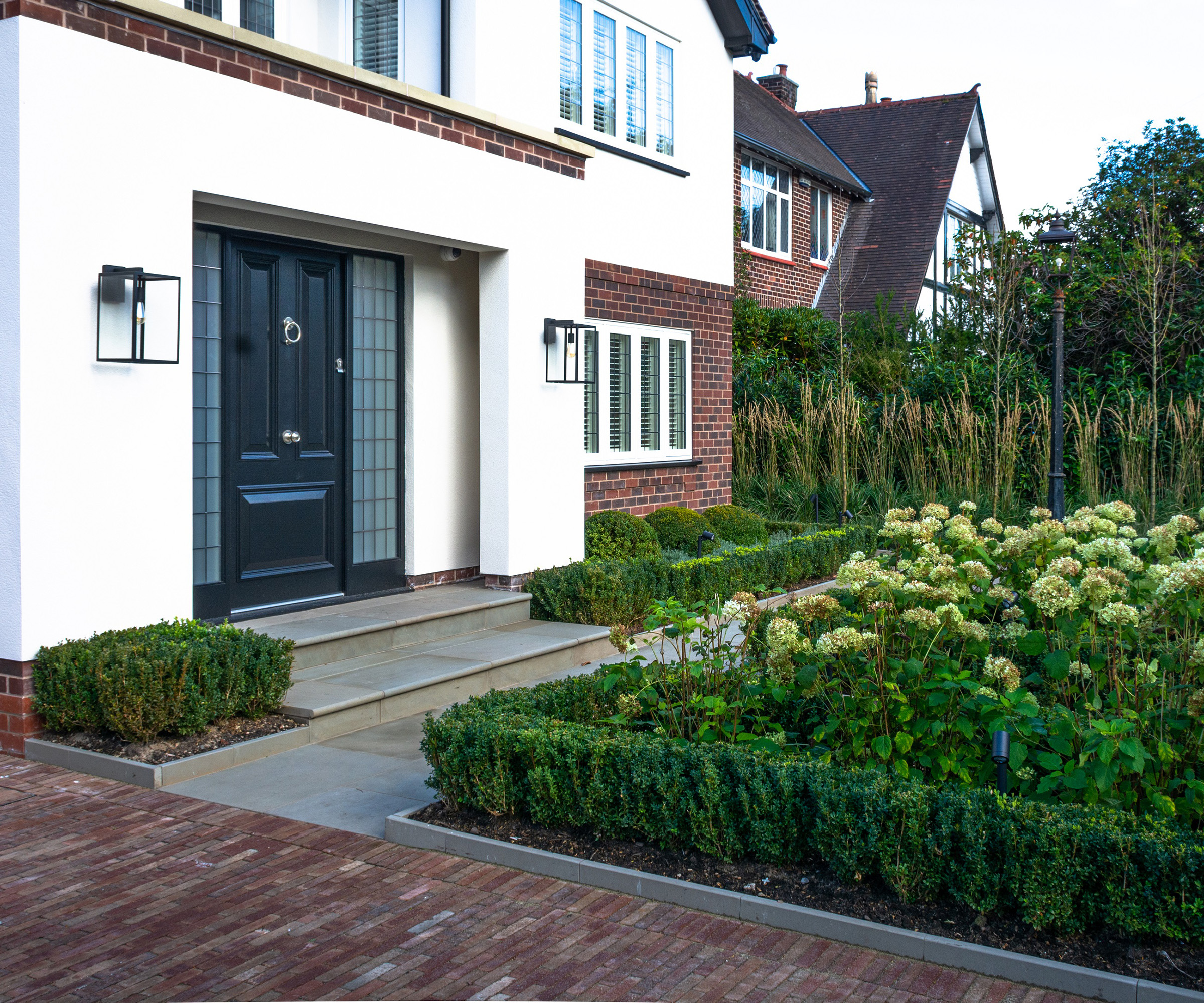 A formal front garden with clipped low hedges and stone garden edging