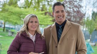 Hannah Swensen&#039;s Alison Sweeney in a winter coat standing next to Victor Webster. Both are smiling.