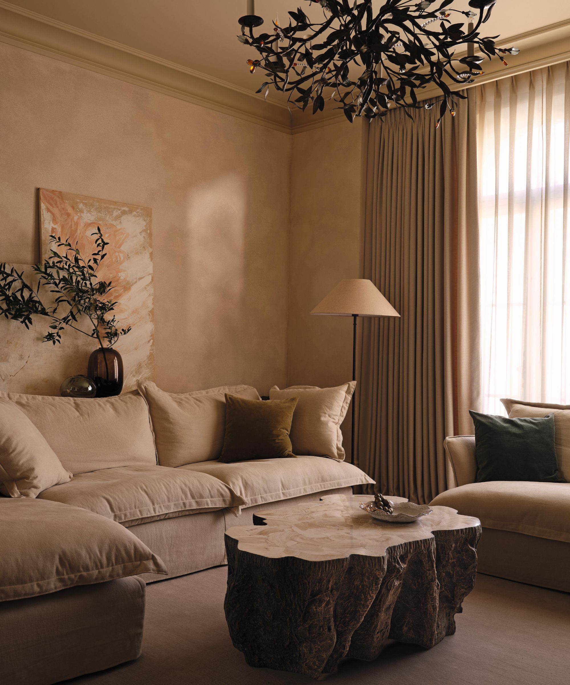 a limewashed neutral living room with big pillow back sofas and a large wooden sculptural coffee table