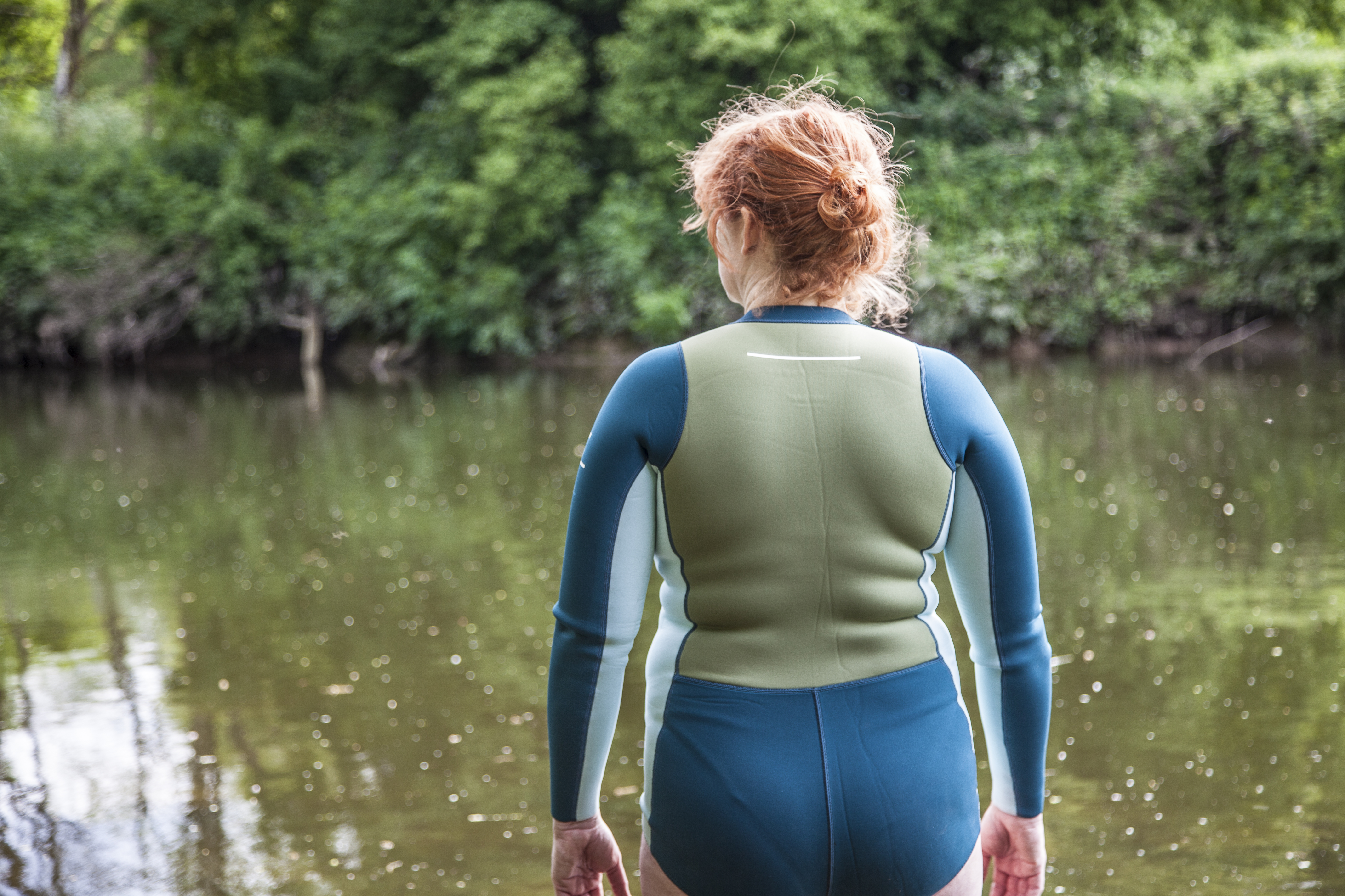 woman wearing Finisterre wetsuit standing in water