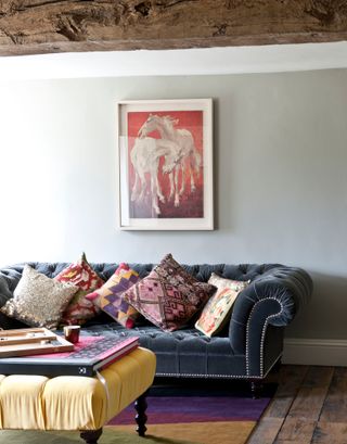 Light grey living room with dark grey sofa and yellow foot stool