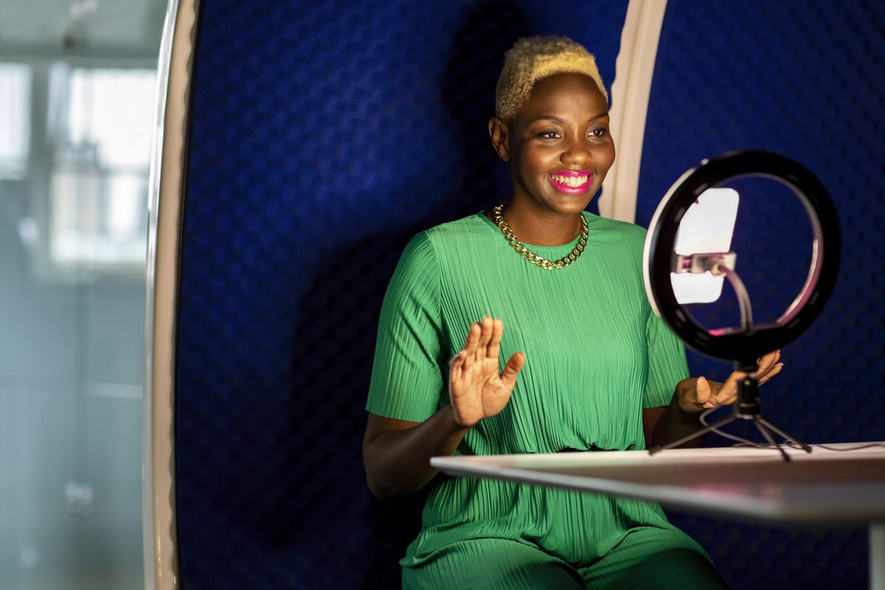 A young female influencer using her phone and a ring light 