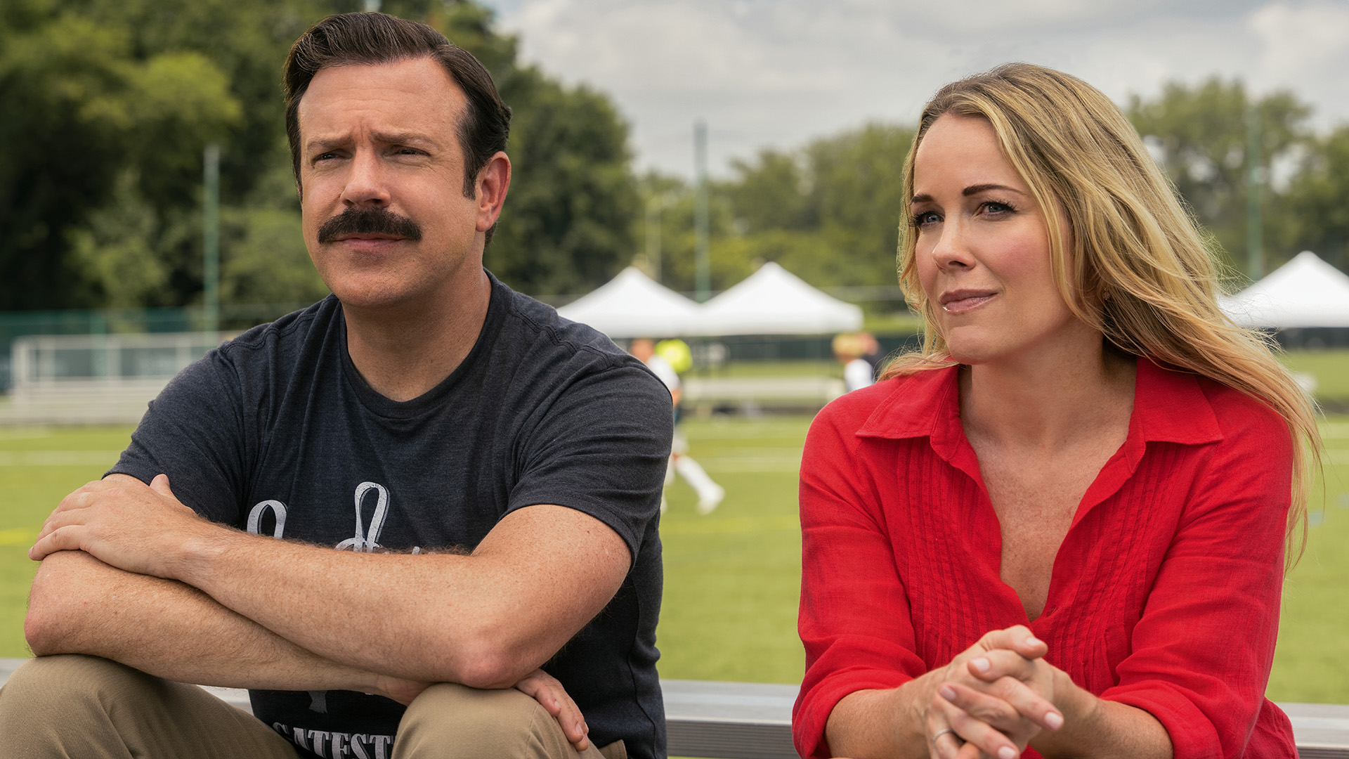 Ted and Michelle sitting on bleacher seating at Henry's soccer game in Ted Lasso season 4