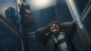 Finney crouched and covering his ears inside a phone booth in Black Phone 2