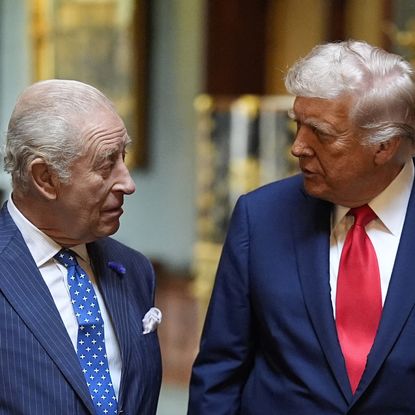 King Charles and Donald Trump talking to each other wearing blue suits