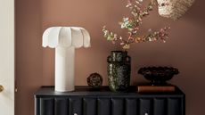 a white table lamp on a console in a pink-beige hallway