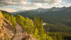 Two women walk along a trail by forest land in Breckenridge, Colorado