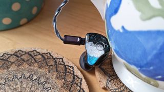 One of the two Ziigaat Horizon IEMs on a desktop. 