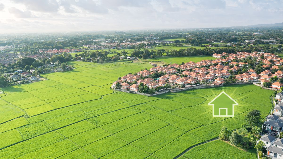 Aerial view of houses curving around edge of green field with icon of house superimposed on field