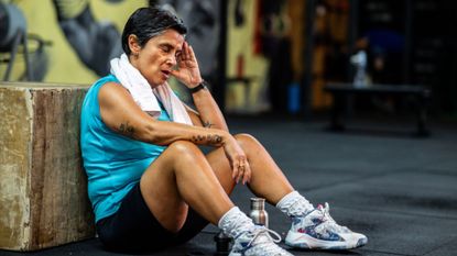 senior woman sits on the floor in the gym to take a rest