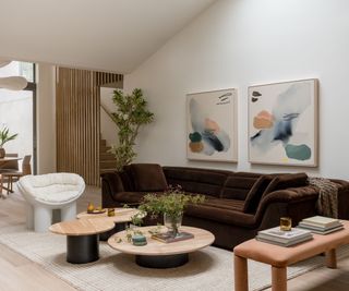 Modern organic living room with brown sofa, round wood tables and abstract art