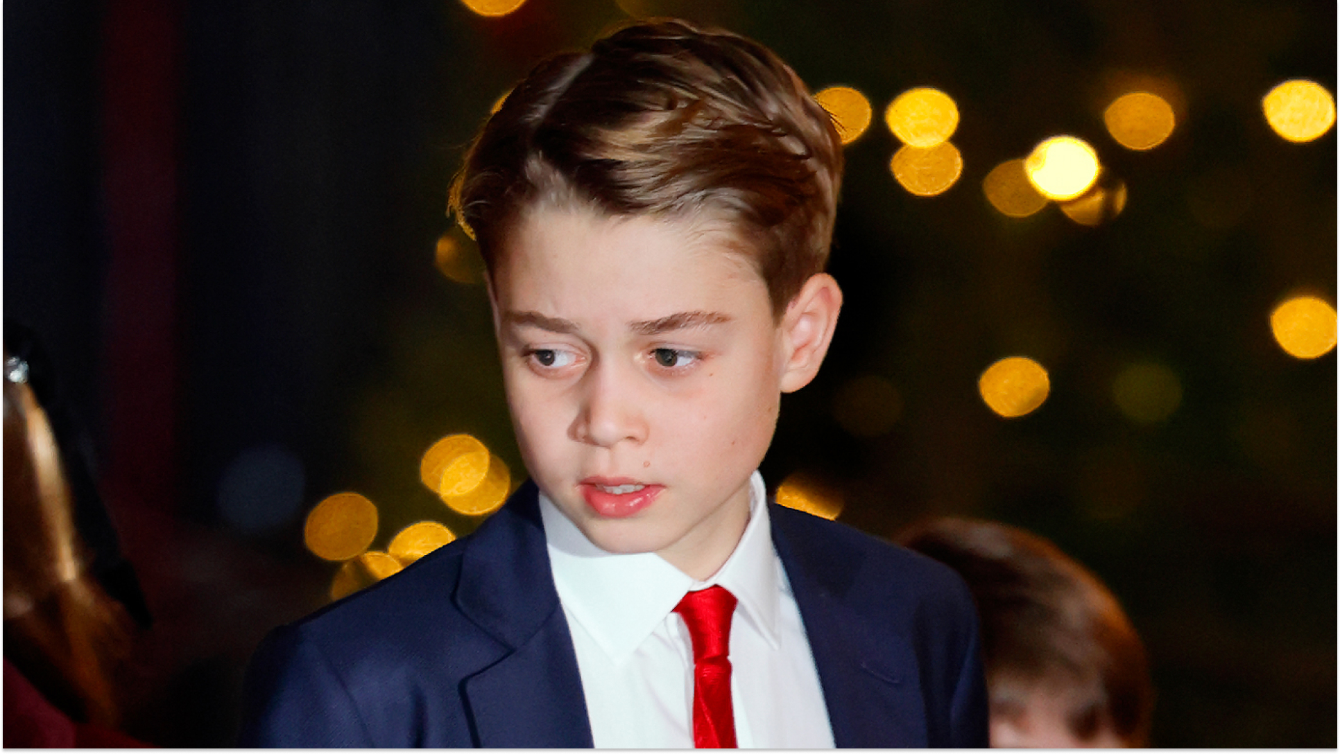 Prince George wears a navy suit, white shirt, and red tie