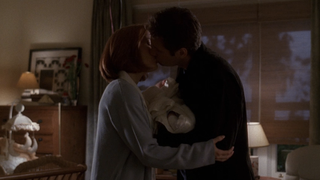 Scully and Mulder kissing over baby William in The X-Files' "Existence"