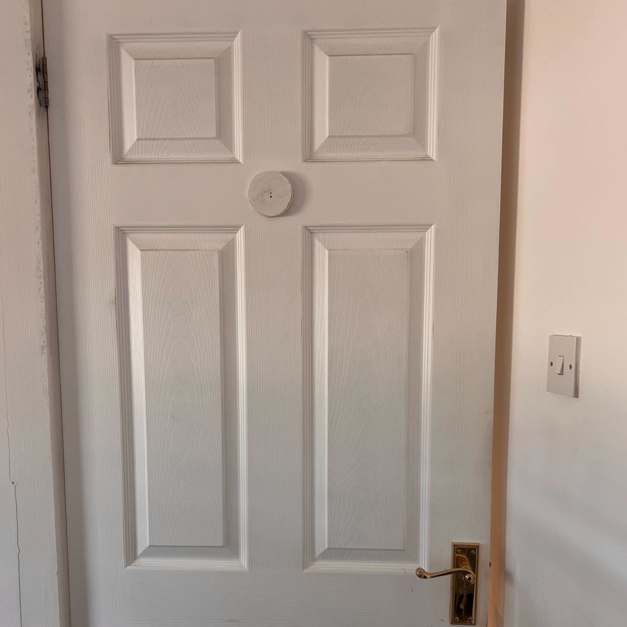 A white, internal door in a white room.