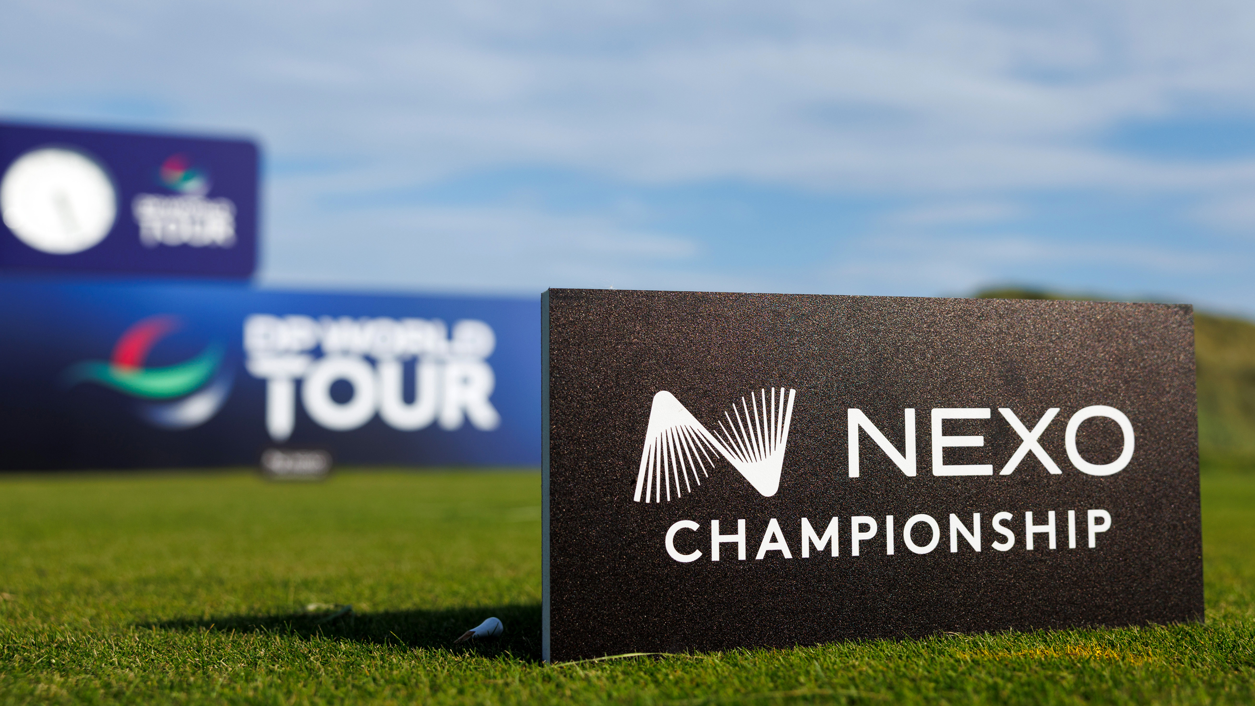 A Nexo Championship sign in the foreground with a DP World Tour sign surround a tee box in the background