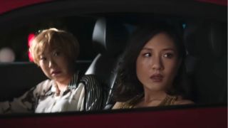 Awkwafina and Constance Wu watching something with surprise from a car in Crazy Rich Asians.