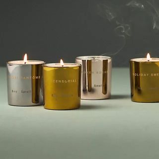 Four candles in alternative gold and silver metal containers. All lit