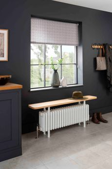 black hallway with radiator with bench on top, peg rail, stone floor and sideboard 