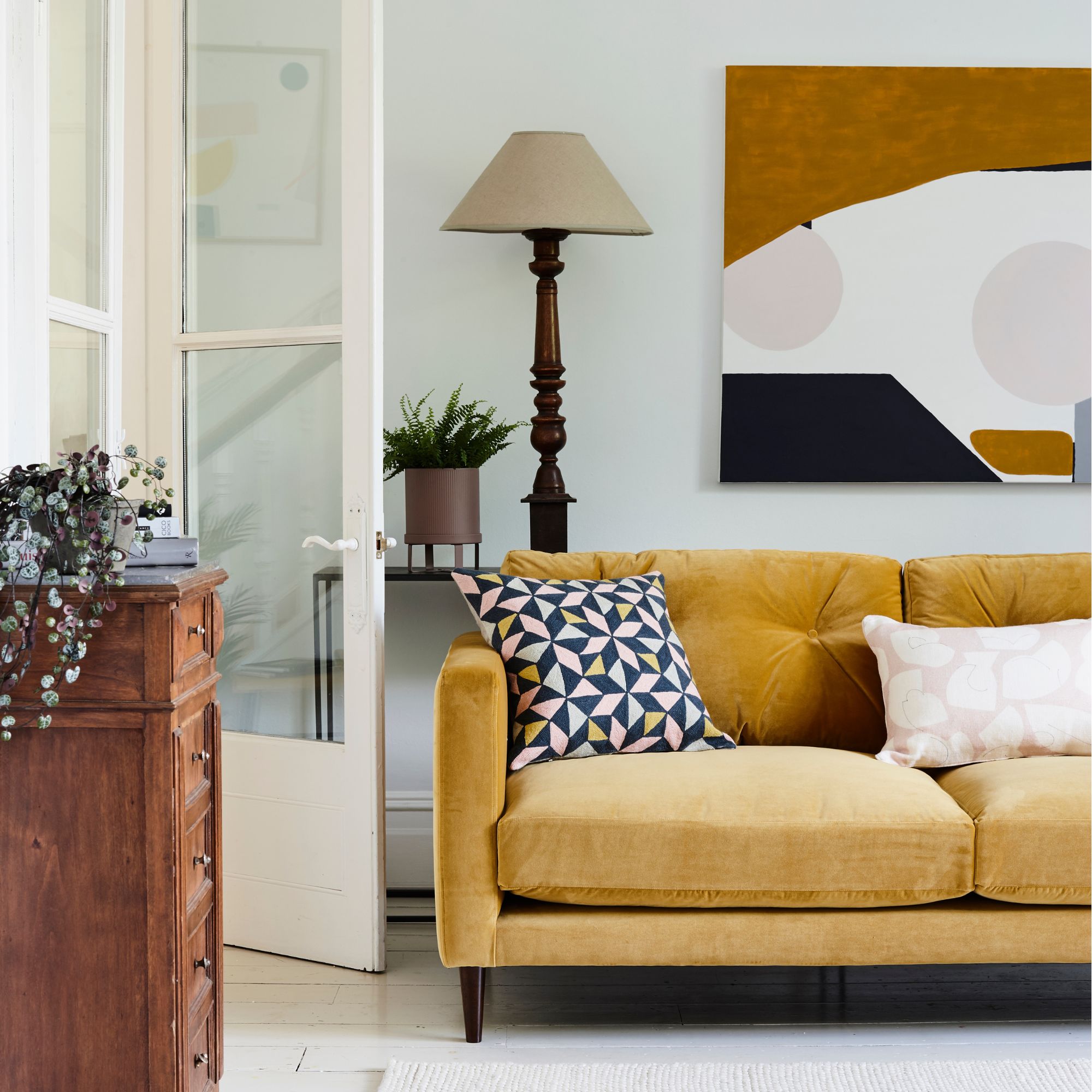 A mustard sofa in a white room with dark wood accents