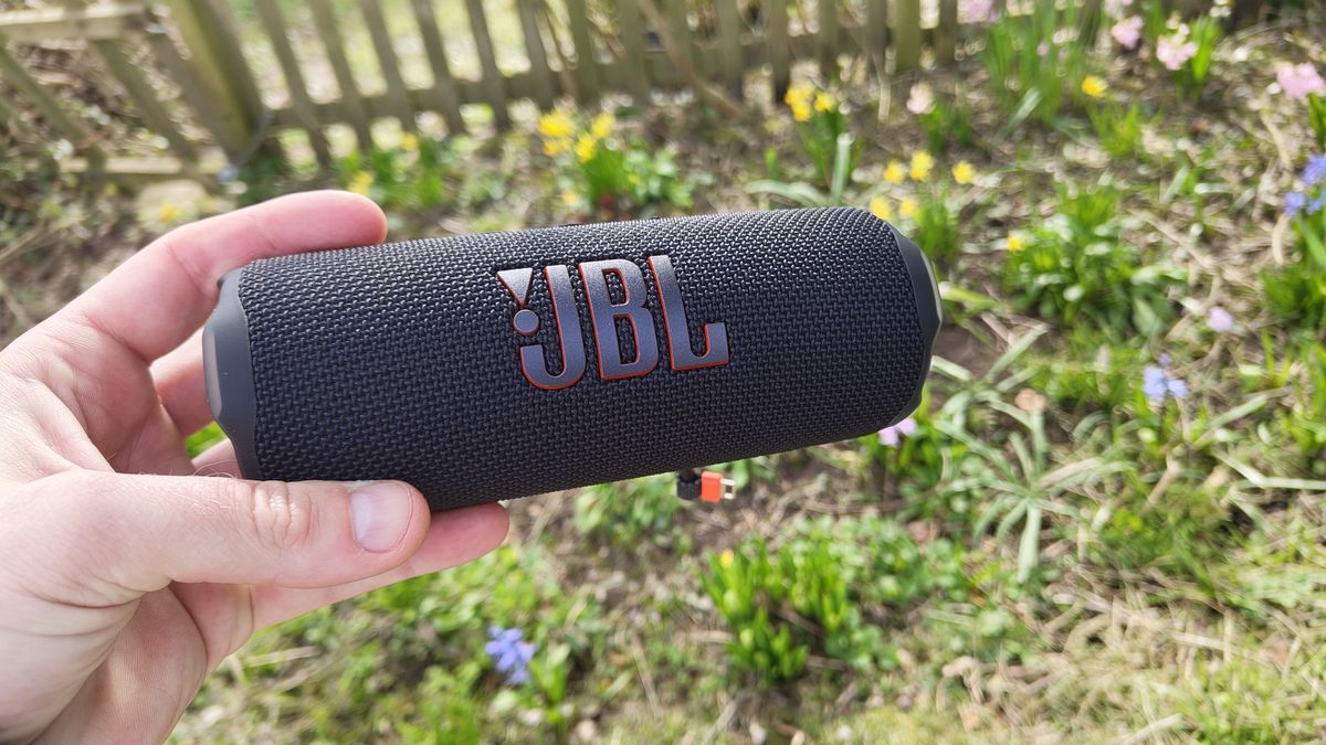 JBL Flip 7 in black held in front of flowers