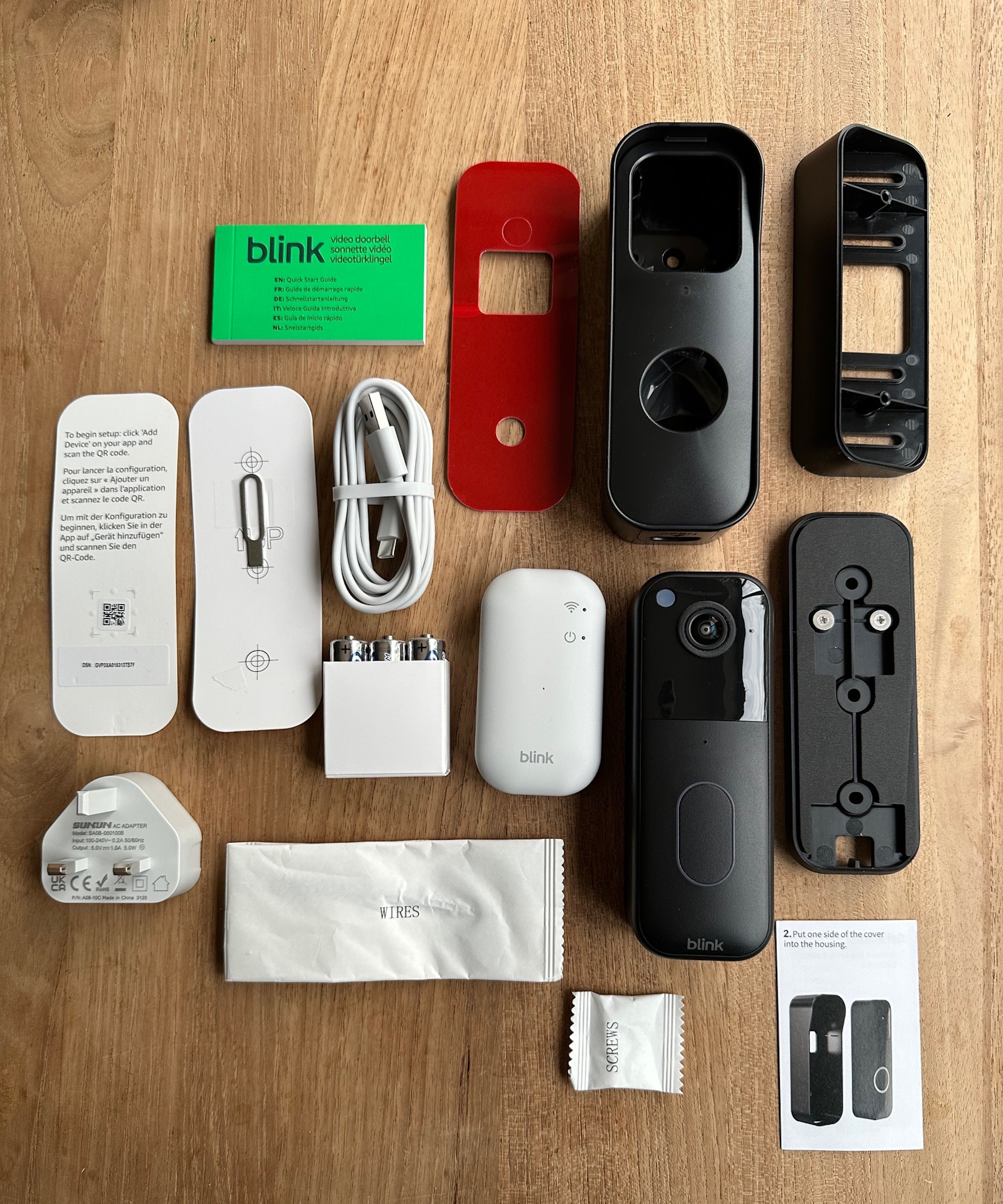 Contents of Blink Video Doorbell box laid out on wooden table.