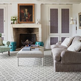 carpet colour trends for 2023, living room with neutral scheme, fireplace, portrait above fire, off white sofa, footstool, off white textured carpet, wall lights, green upholstered armchair, teal footstools