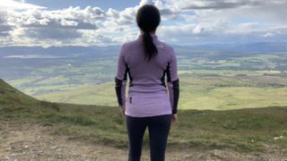 Rear view of a hiker wearing a purple fleece looking at the view