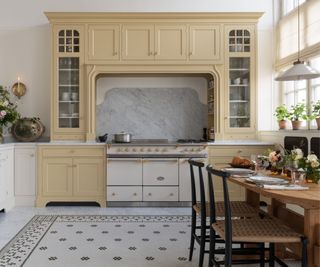 A two-tone kitchen with white cabinetry and butter yellow cabinets framing the range cooker