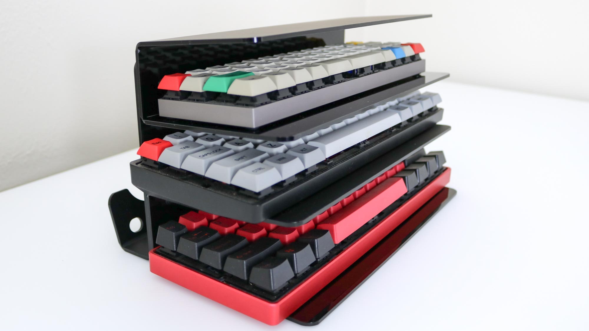 Three keyboards placed on the shelves of a keyboard storage rack