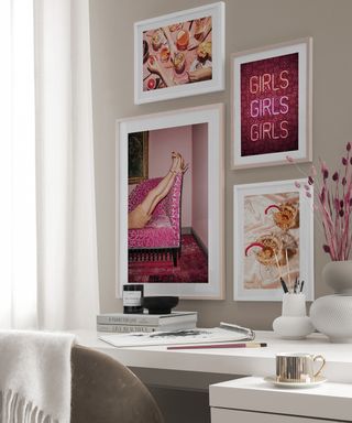 Gallery wall in home office with pink prints by Desenio, and a white desk with essentials on it, and a grey chair